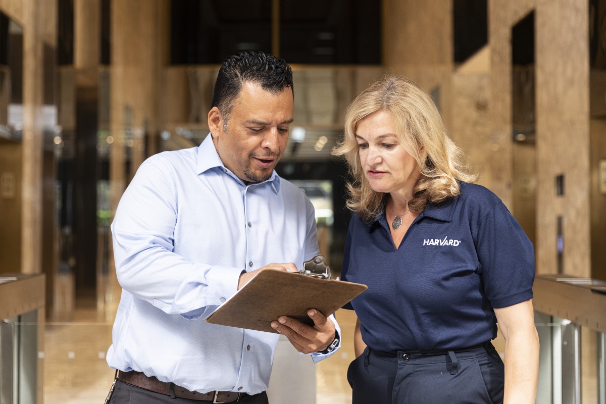 Two people reviewing a document on a clipboard in an office lobby.