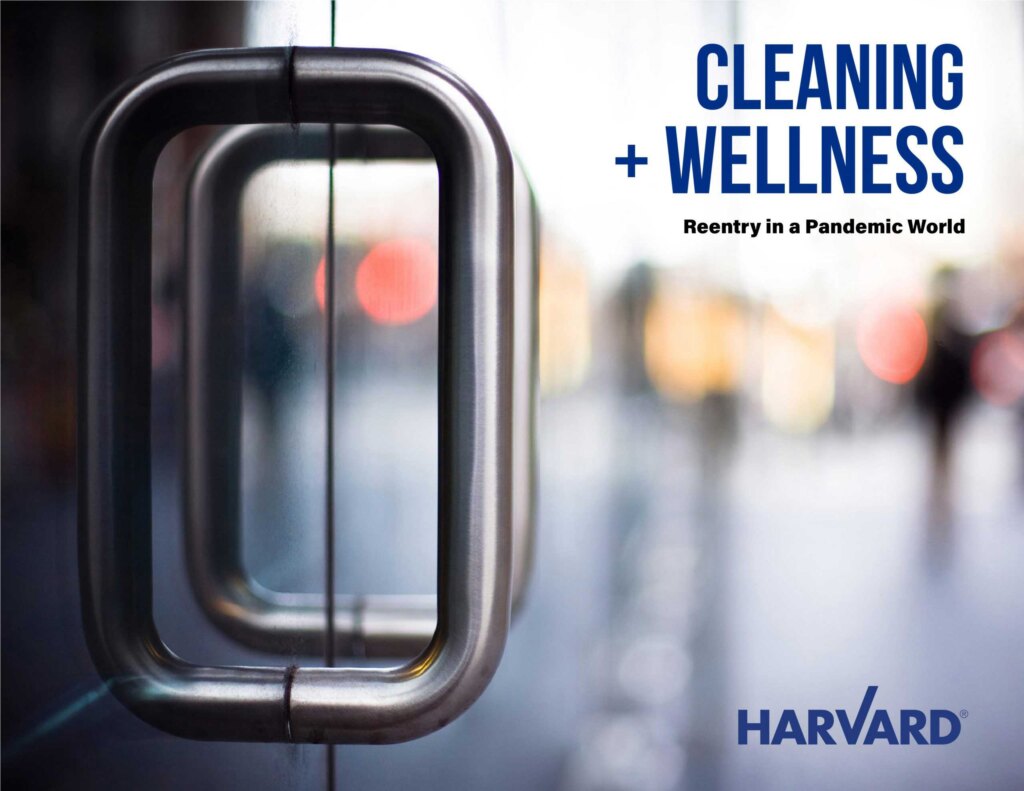 Close-up of a glass door handle with text: "Cleaning + Wellness" and "Harvard" logo.